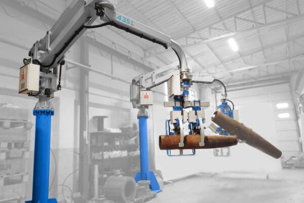 Operator guiding a pneumatic manipulator with a custom gripper while positioning an industrial component at a workstation