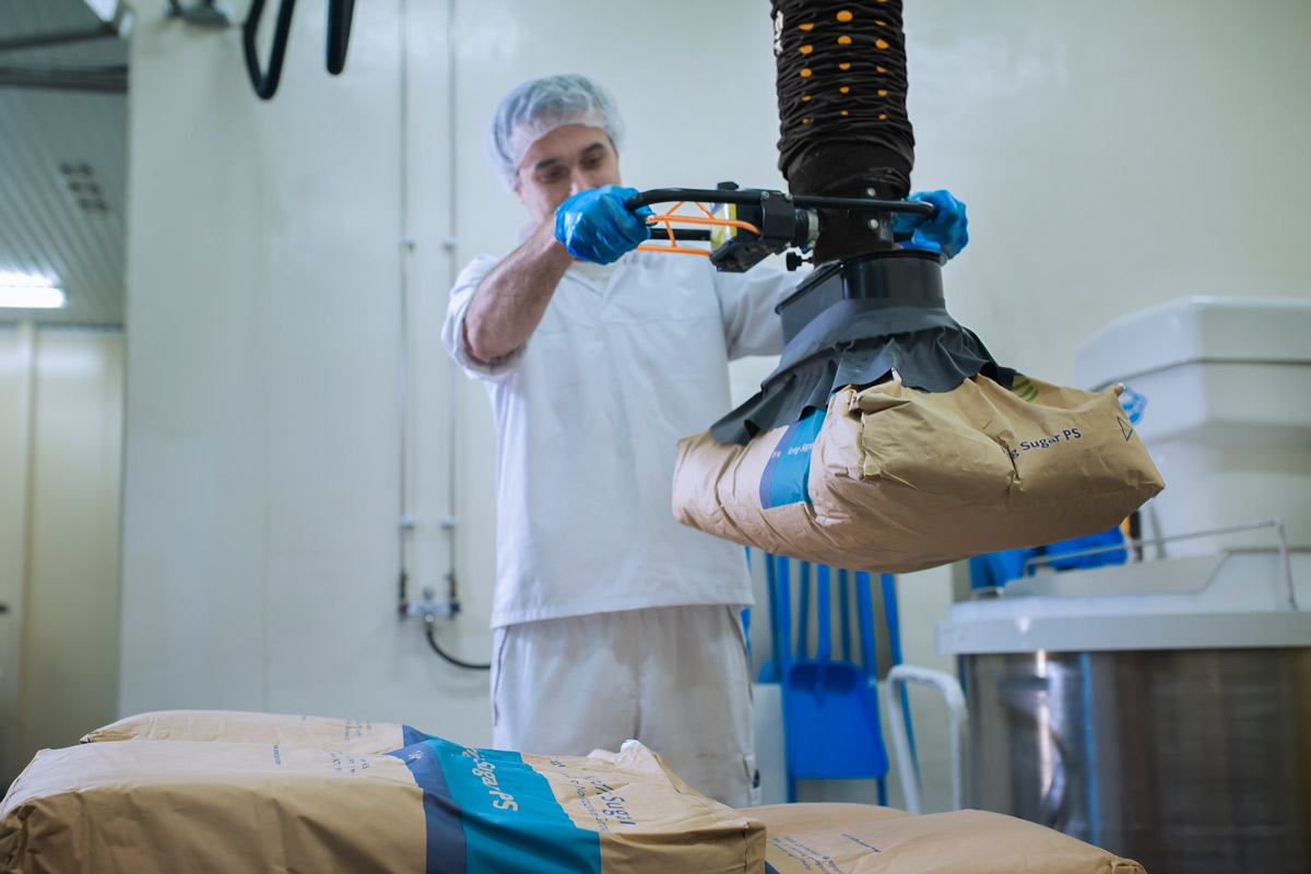 Food grade pneumatic manipulator handling drums and sacks in beverage manufacturing facility.