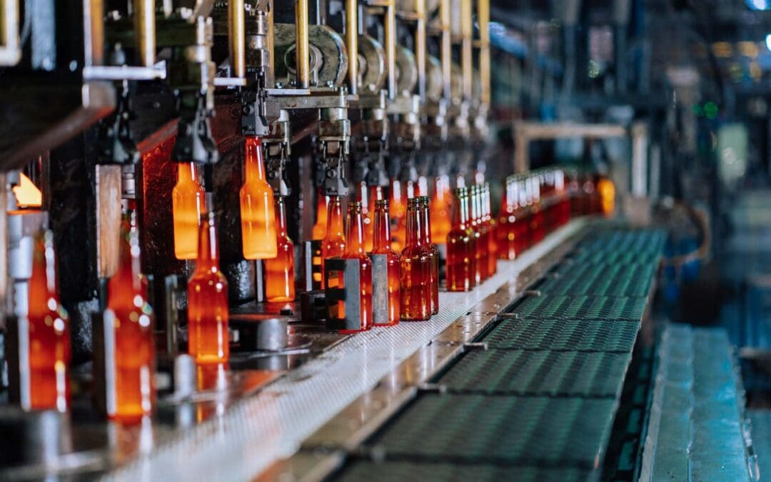 Amber glass bottles moving through an automated filling line on a beverage bottling conveyor